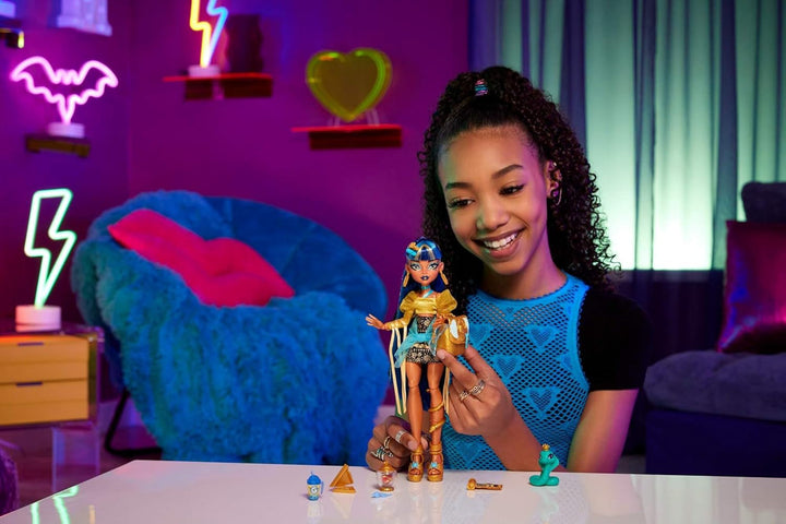 Păpușă Monster High Cleo De Nile în bluză aurie și fustă stratificată, include animal de companie Cobra Hissette și accesorii precum rucsac, gustare și rolă de hârtie, HXH74 Papusi Naty Shop